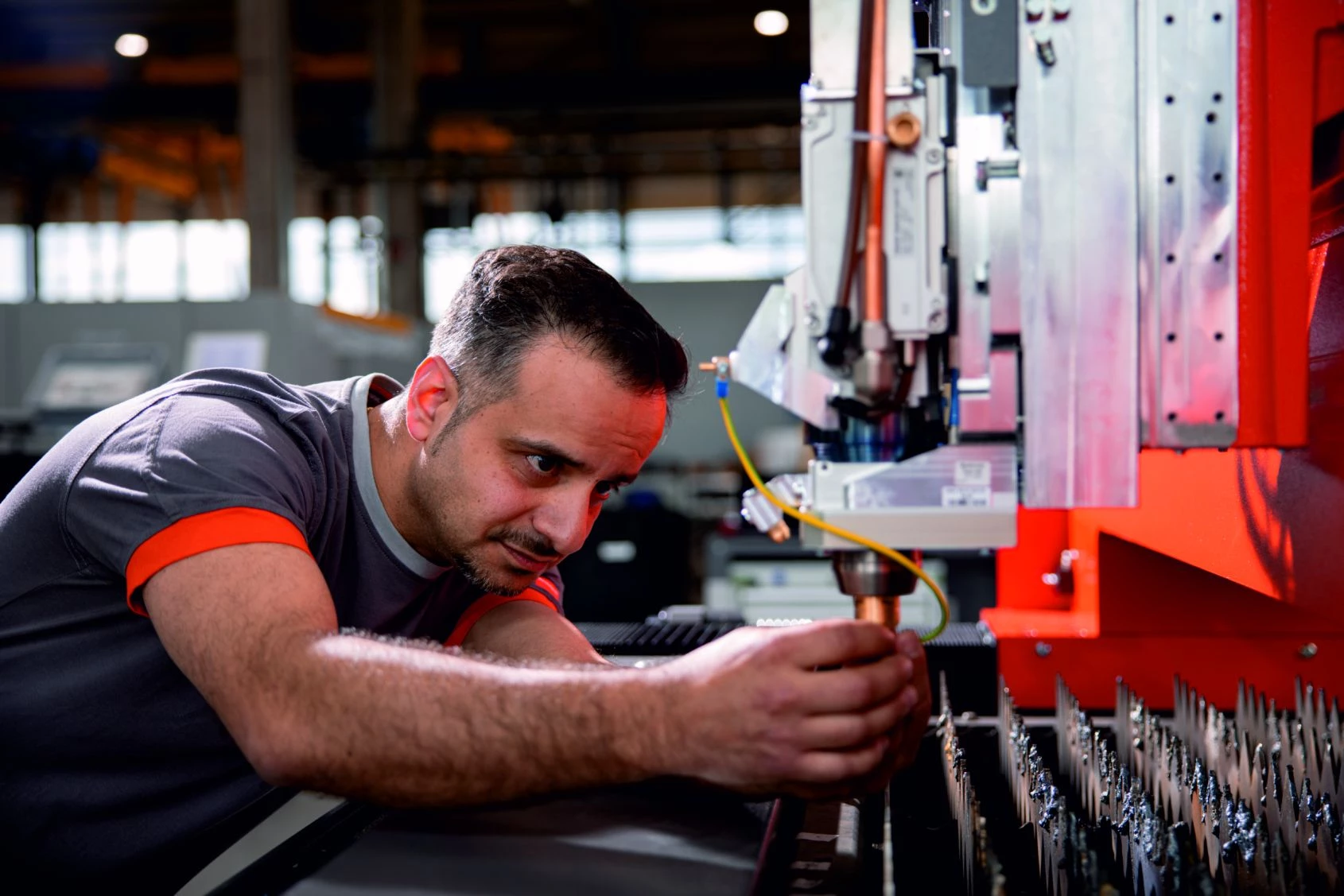 Technician inspecting and adjusting an industrial fiber laser cutting head